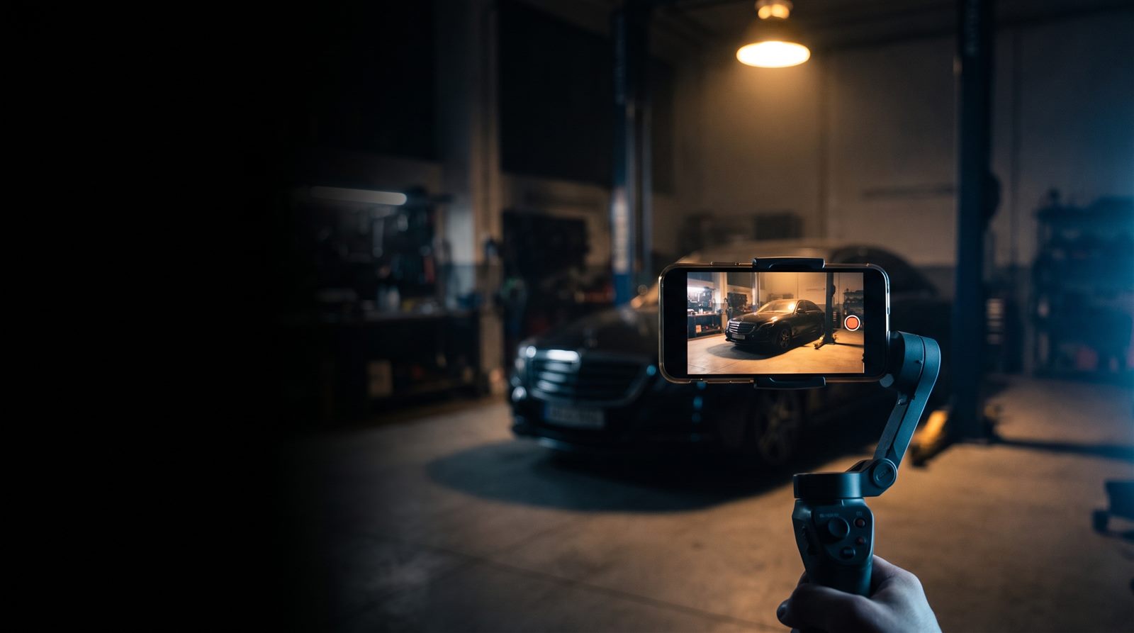 Celular em estabilizador filmando um carro numa oficina à noite
